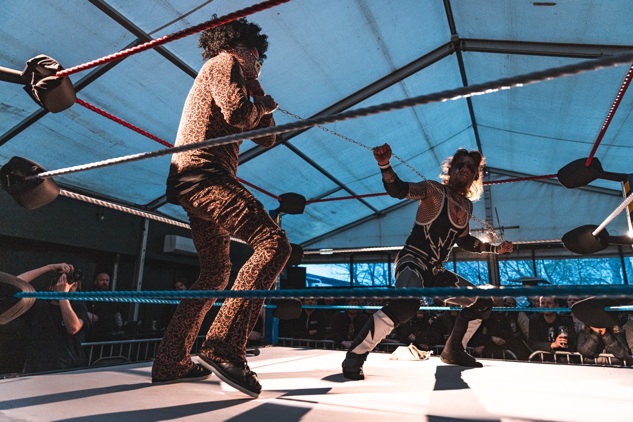 Cinematic shot of a wrestling ring under dramatic neon lighting with atmospheric smoke and intense cyan and magenta highlights
